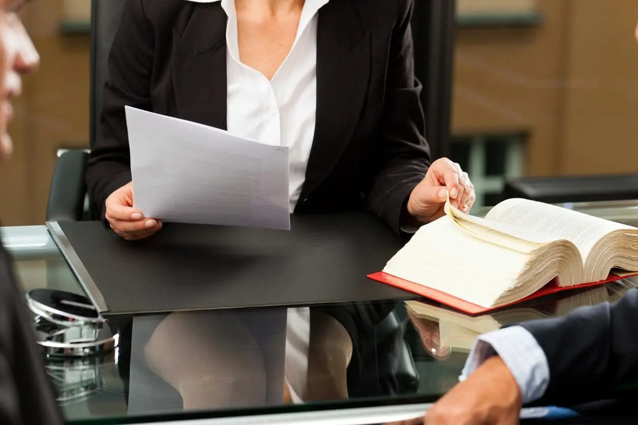 A woman is holding papers while sitting at a table.