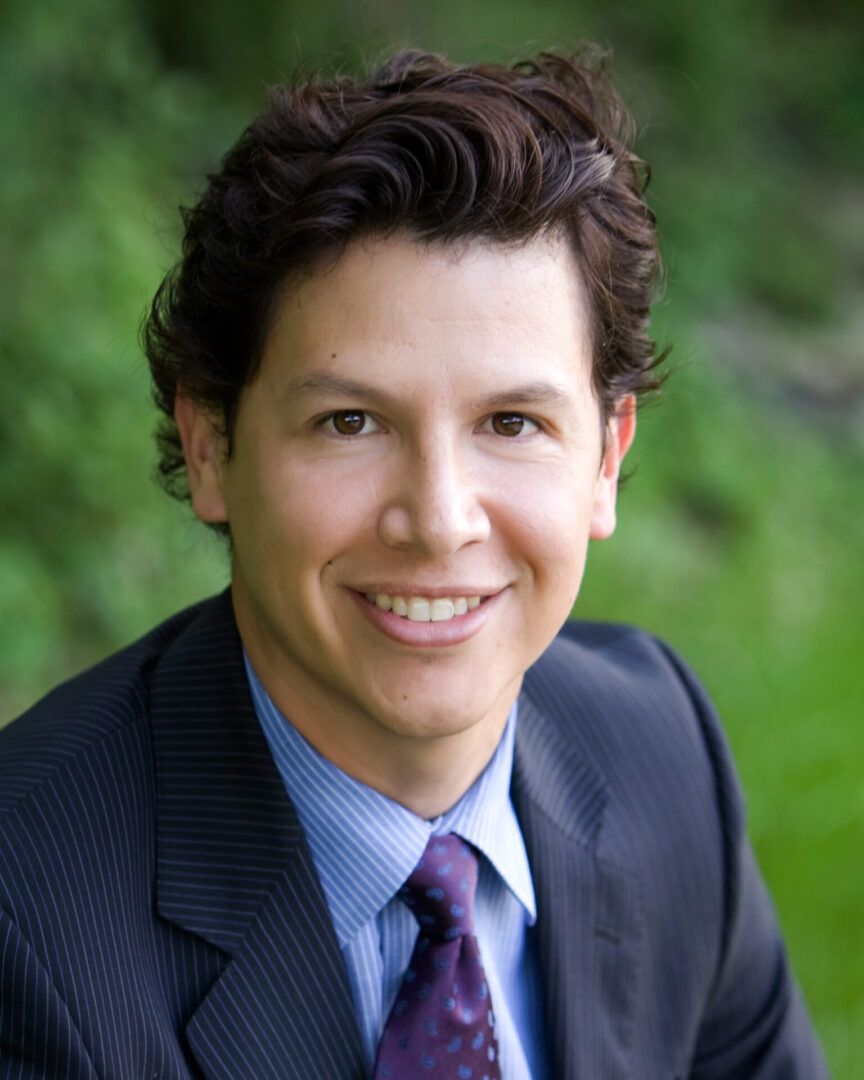 A man in suit and tie smiling for the camera.